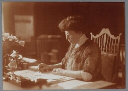 Portret van Lizzy van Dorp, aan het werk achter haar bureau 1915 ?