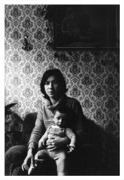Allochtone vrouw zit met haar kind op schoot op een bank in haar huiskamer in Nederland. 198?