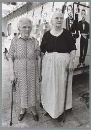Twee oudere vrouwen, waarvan één in Scheveningse klederdracht. 1987