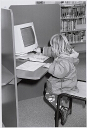 Meisje , kleuter, achter een computer in een bibliotheek. 1998