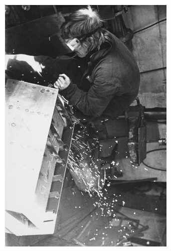 Vrouw bewerkt met slijptol metaal voor de bouw van een kachel. 1981