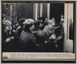 Bijschrift: 'Duw- en trekwerk van politie en betogers tijdens de ontuiming van het bezette huisvestingsbureau van de gemeente'. 1983