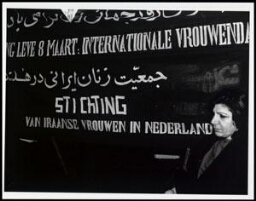 Vrouw staat voor spandoek met de tekst: 'Lang leve 8 maart: internationale vrouwendag 199?