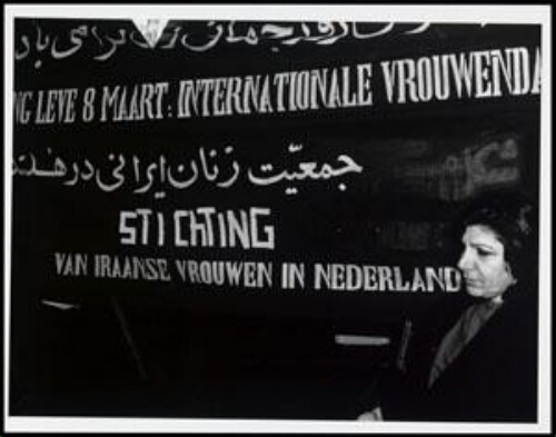 Vrouw staat voor spandoek met de tekst: 'Lang leve 8 maart: internationale vrouwendag 199?