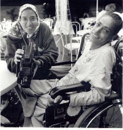 Twee spastische bezoeksters, één met camera de andere in een rolstoel, tijdens de Wereldspelen voor Gehandicapten 1990