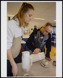 Verzorgster kijkt toe hoe een verstandelijk gehandicapte een kopje koffie inschenkt 200?