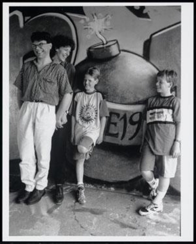 Vader, moeder en twee zonen staan tegen een graffiti muur geleund 1995