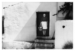 Algerijnse vrouw staat in haar deur, met een mand vol aardappels. 197?