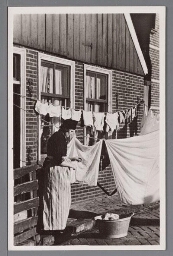 Vrouw in Volendamse klederdracht hangt de was op. 1900?