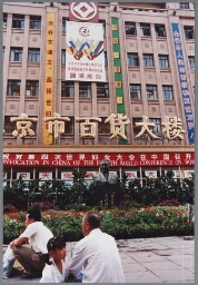 Vooraanzicht van het grootste warenhuis in Beijing, met spandoeken in het Chinees en de Engelse tekst: Equality development peace en één over de breedte van de gevel: (c)onvocation in China of the fourth world conference on wom(en) 1995