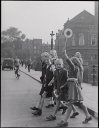 Klaar-over, lid zijn van de verkeersbrigade, helpt met stopbord mede-scholieren met oversteken 1949