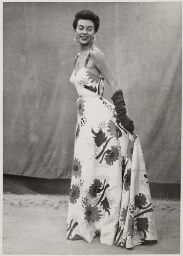 Vrouw toont jurk, gemaakt van de stof op foto met identificatienummer 16563. 195?
