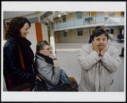 Verzorger met twee verstandelijk gehandicapten, in het midden in de rolstoel Corry Barten en daarnaast Aaf, met witte jas 2004
