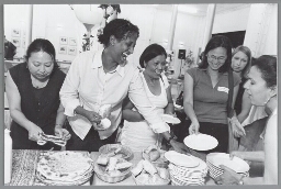 Deelneemsters aan de bijeenkomst 'Jong en Oud: Vrouwen/Bewegingen door de Tijd heen' eten samen eten bereid door vrouwen van Prime 2003