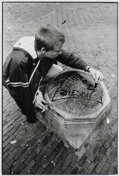 Vrouw schrijft tekst in driehoek: 'ik ben lesbies hoera' op een groot stuk steen op straat. 1982