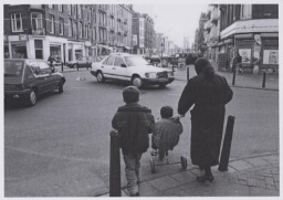 Bijschrift: 'Onoverzichtelijk kruispunt waar een vrouw met haar kinderen de weg oversteekt' 199?