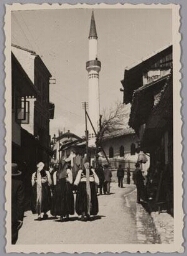 Straatbeeld met vrouwen in klederdracht, op de achtergrond een minaret in Sarajevo. 193?