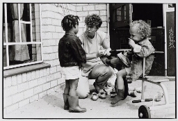 Begeleidster van kinderdagverblijf 'de Speeltoren' in de Pijp met buurtkinderen. 1986