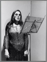 Een zingende vrouw met voor haar een boekje met de titel 'A litany for women artists'. 1987