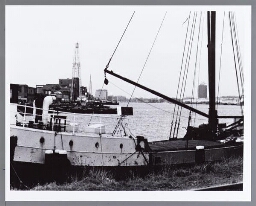 Boot in de IJ-haven vanaf verbindingsdam met links Oostelijke Handelskade en het Shellgebouw 1991