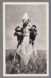 Meisje in Volendamse klederdracht, met twee poppen in haar armen, eveneens in klederdracht. 1900?
