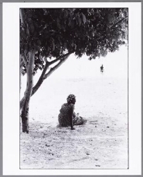 Vrouw met krulspelden zit aan het strand 1986