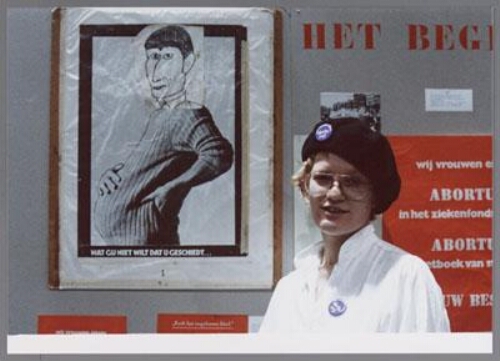 Activist  met buttons voor poster van een zwangere Van Agt, tijdens de abortusmanifestatie in de Jaap Edenhal 1978. 1978