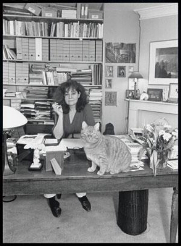 Portret van Anja Meulenbelt achter haar bureau met een sigaar in de hand en met haar poes. 1993
