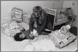 Illustraties bij het thema 'Wie zorgt er voor het huishouden als er geen huisvrouwen meer zijn ?' Vrouw verschoont een baby. 1989